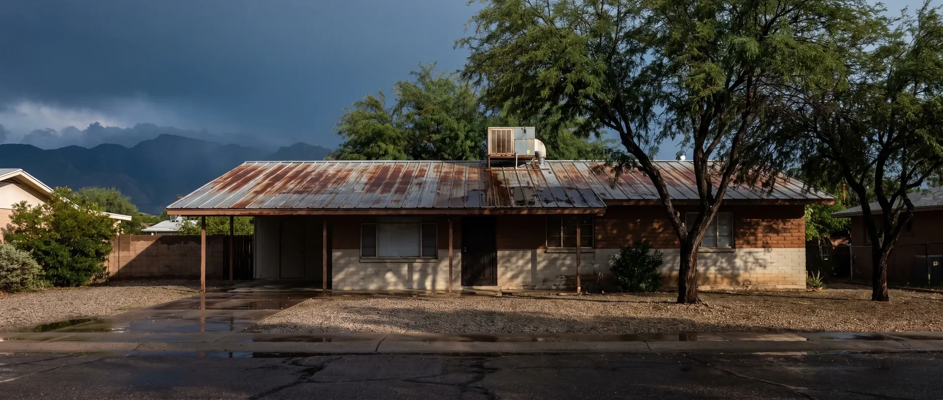 Midcentury Tucson ranch house with a low pitched metal roof and a rooftop swamp cooler