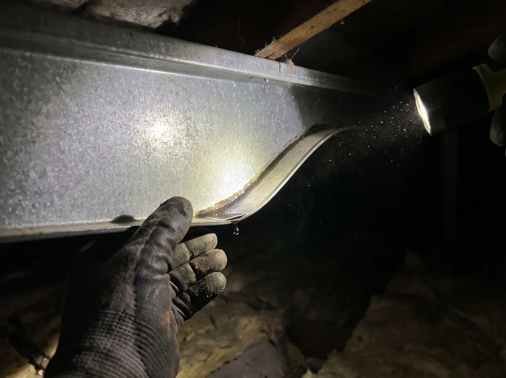 Water tracking along the underside of a metal roof purlin, traced back toward the leak entry point
